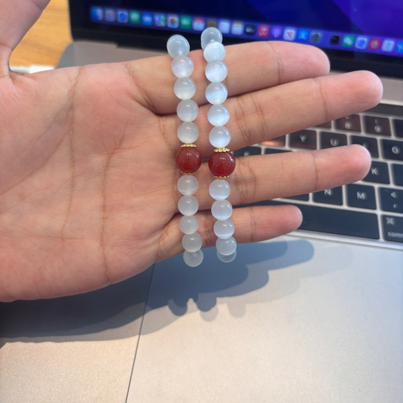 Handmade white bead and red agate bracelet held in hand