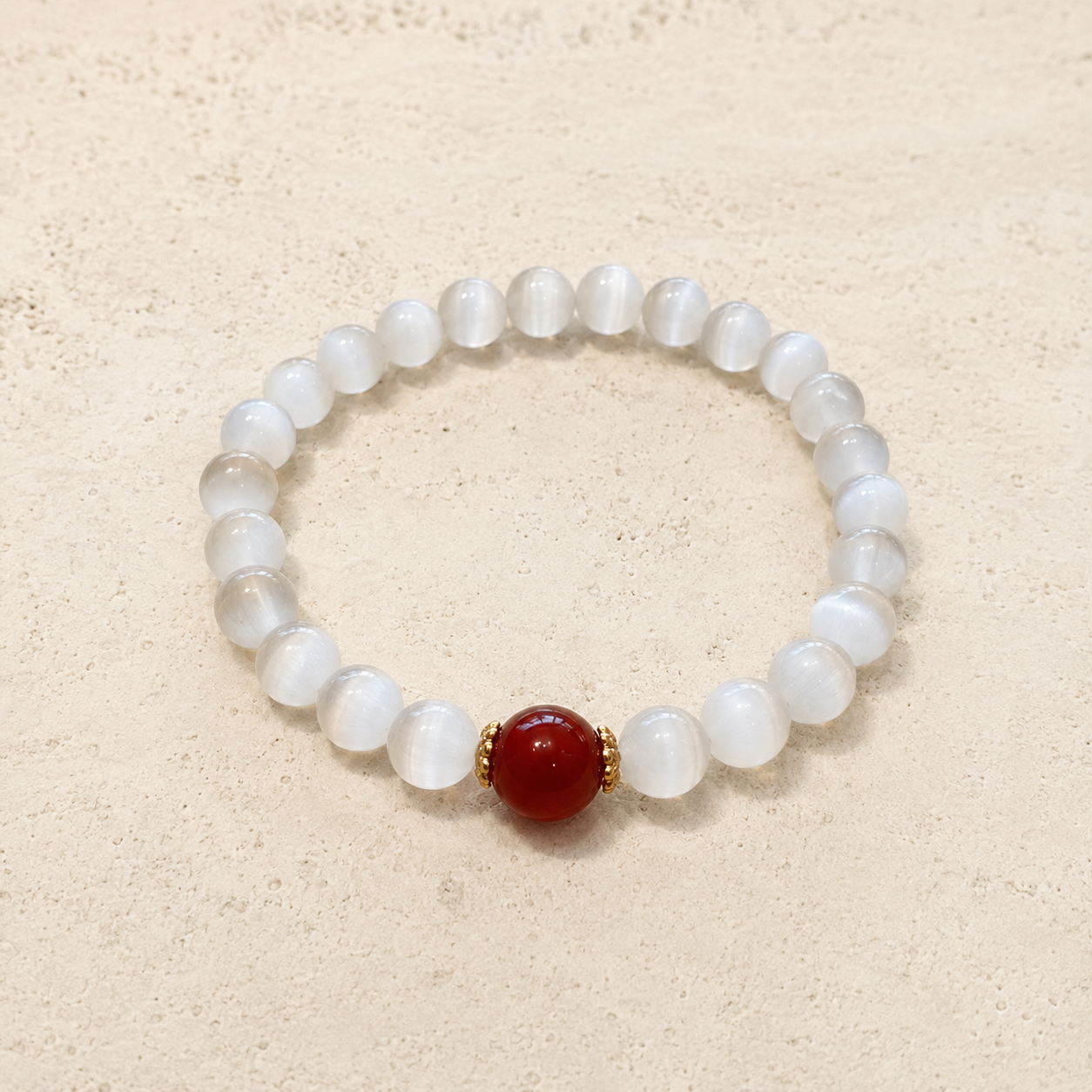 Two white bead red agate bracelets on stone surface