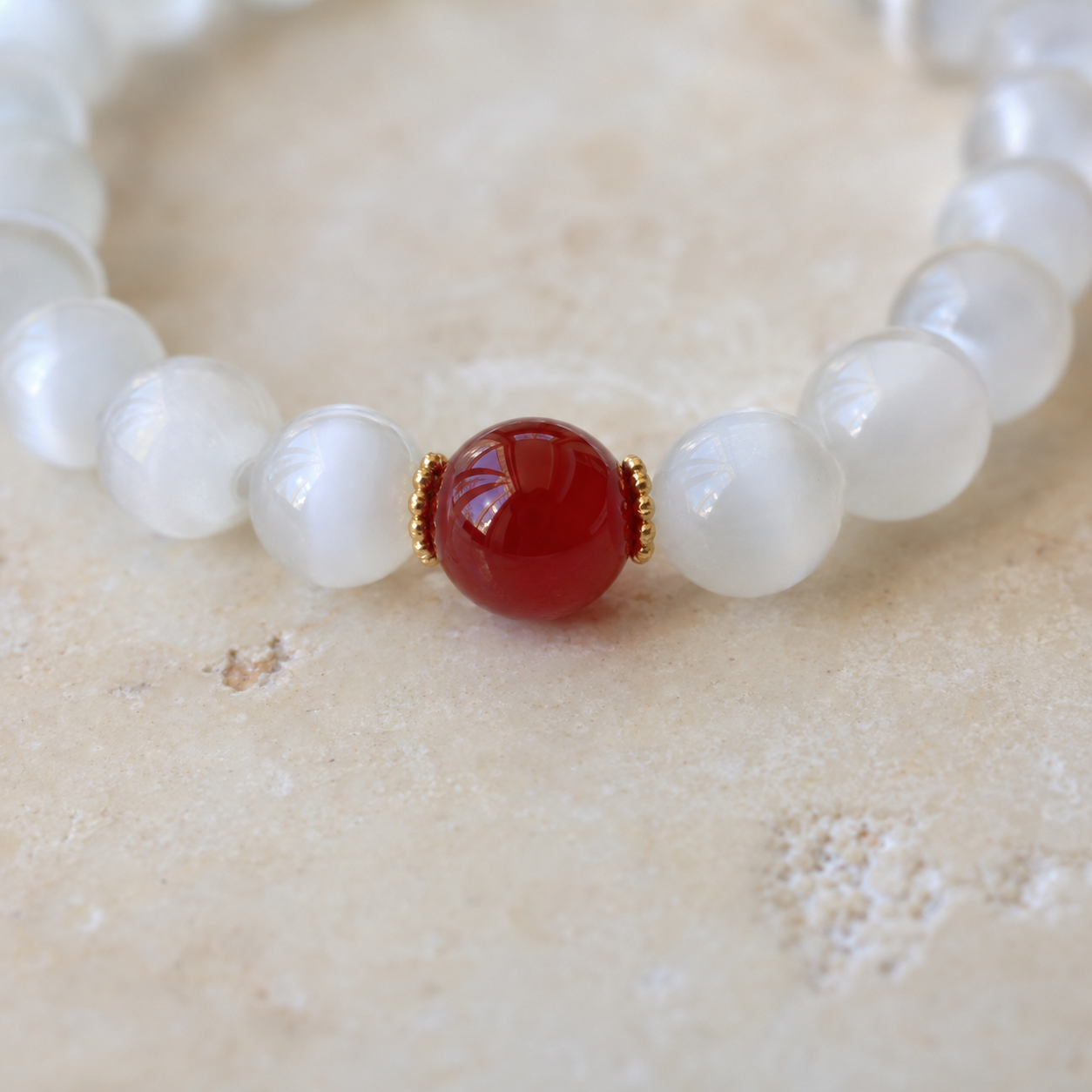 Single white bead red agate bracelet on stone